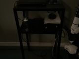 un petit bureau sur lequel est posé un ordinateur portable, dans l'obscurité