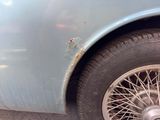 a close up of a blue car with a rusted tire
