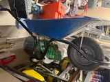 a blue wheelbarrow in a garage filled with tools