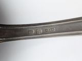 a silver spoon with a handle on a white surface