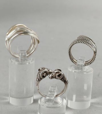 three different rings in a clear glass holder on a white surface