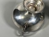 a silver vase with a key in it sitting on a table