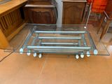 a glass table with wheels on it in the middle of a room