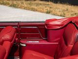 the interior of a red convertible car with leather seats and a steering wheel