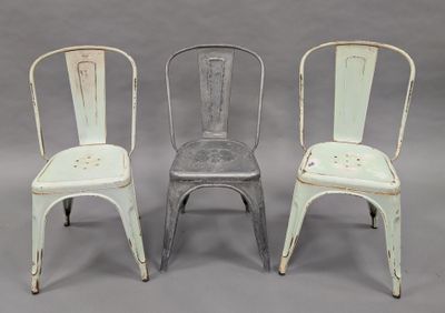 three metal chairs sitting next to each other on a gray surface