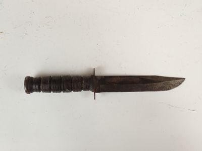 an old knife that is laying on a white surface