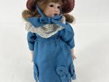 une poupée qui porte une robe bleue et un chapeau