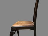 a wooden chair with a leather seat on a gray background