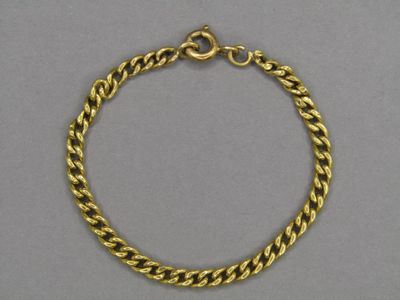 a gold chain bracelet with a clasp on a grey background