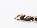 a close up of a black and gold bracelet on a white surface