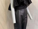 Le mannequin porte un pantalon en cuir noir et un haut noir.