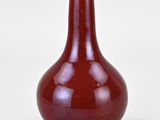 a red vase that is sitting on a white surface