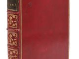 un vieux livre avec une couverture rouge et des bordures dorées sur fond blanc