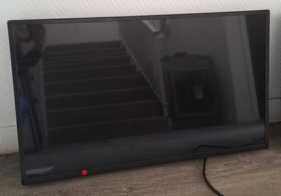 un téléviseur à écran plat posé par terre à côté d'une enceinte