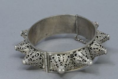 an antique silver bracelet with filigree design on a grey background