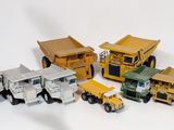 plusieurs camions jouets sont alignés sur une surface blanche