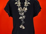 a woman ' s black shirt with gold embroidery on it