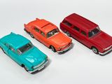 trois petites voitures sont alignées sur une surface blanche