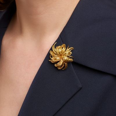 un gros plan sur une femme portant une broche en forme de fleur dorée