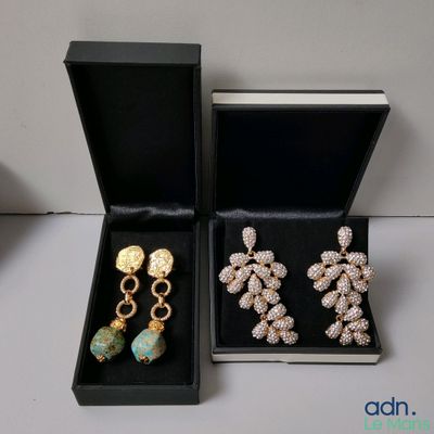 Deux paires de boucles d'oreilles se trouvent dans une boîte noire posée sur une table.