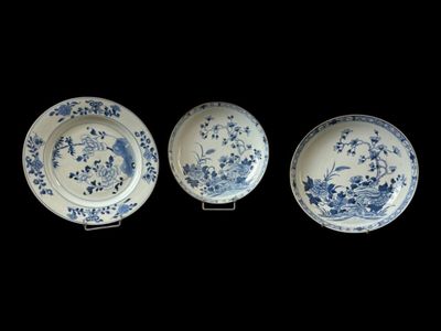 three blue and white plates with birds and flowers on them