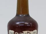 bottles of liquor are sitting on a wooden table with a white wall in the background
