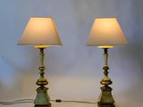 pair of green and gold table lamps with white shades on a white background