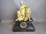 une statue en or représentant une femme avec une horloge posée sur une table