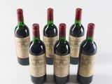 six bottles of wine are lined up in a row on a white surface