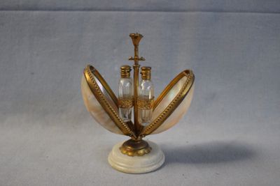 un vase doré et blanc sur lequel sont posées deux bouteilles