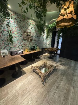 a room with a table, chairs, and a plant on the wall