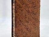 an old book with a brown cover sitting on top of a white surface