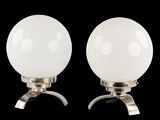 une paire de lampes de table en verre blanc en forme de globe, montées sur des pieds en métal