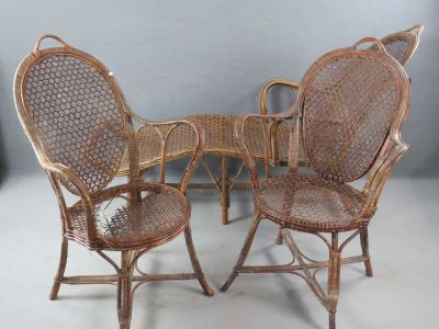 trois chaises en osier et une table sur laquelle est posé un oiseau