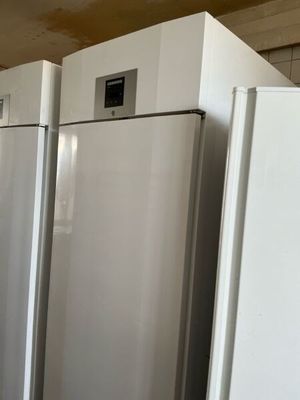 several white refrigerators are lined up in a row in a kitchen
