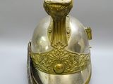 un vieux casque en laiton orné d'une plume sur le sommet