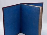 an open blue book sitting on top of a white surface