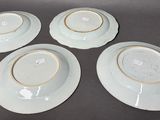 four white plates with gold rims are sitting on a table