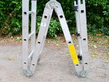 a pair of ladders sitting on the ground next to a bush