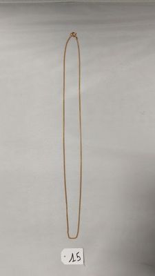 un collier en or dont l'extrémité est ornée d'une longue chaîne