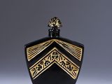 a black and gold perfume bottle sitting on top of a white surface
