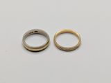 two gold wedding rings on a white surface