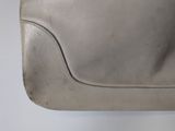 someone is holding a silver purse with a handle on a white surface