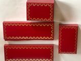 trois boîtes rouges ornées de bordures dorées sont empilées les unes sur les autres