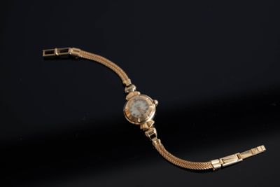 gros plan d'une montre en or sur une surface noire
