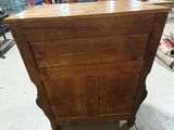 a wooden chest of drawers in a room with a chandelier