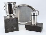 two silver vases and a silver plate on a table