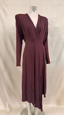 La robe est bordeaux, elle a des manches longues et un col en V.