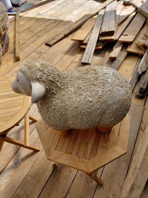 un mouton assis sur une table en bois