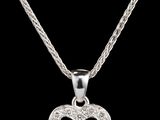 un pendentif en forme de cœur en diamant, suspendu à une chaîne, sur fond noir